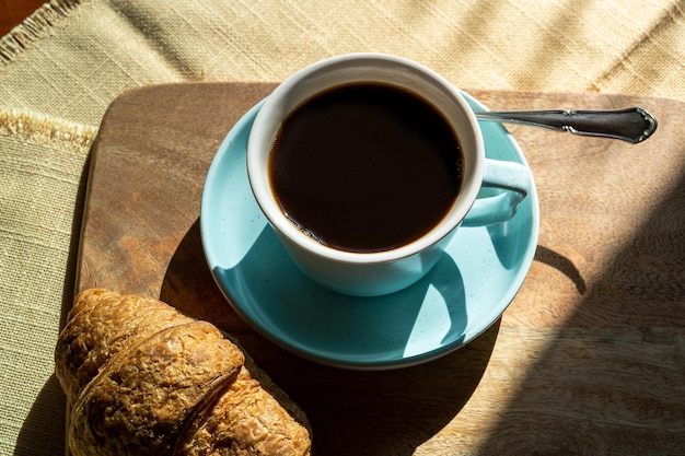 Cup of coffee and croissant illuminated by sunlight  autumn day