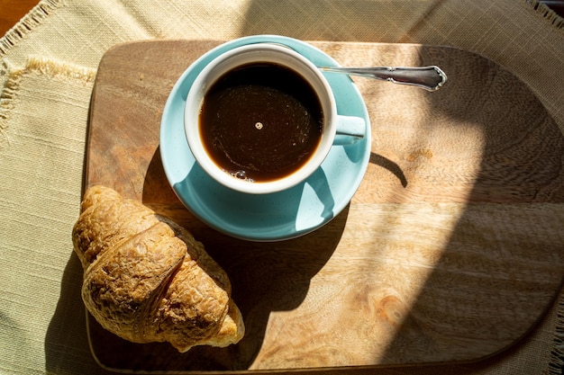 Cup of coffee croissant illuminated by the sunlight autumn day