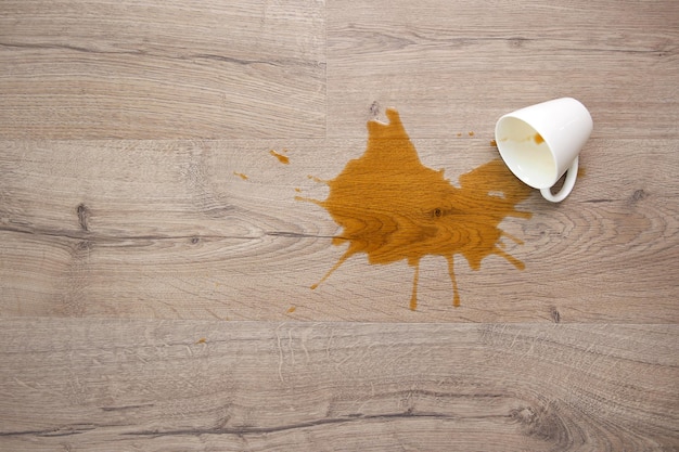 Photo a cup of coffee fell on laminate coffee spilled on floor focus on the puddle flat lay top view