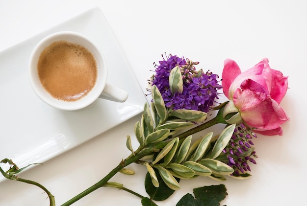 A cup of coffee and flowers on a white table