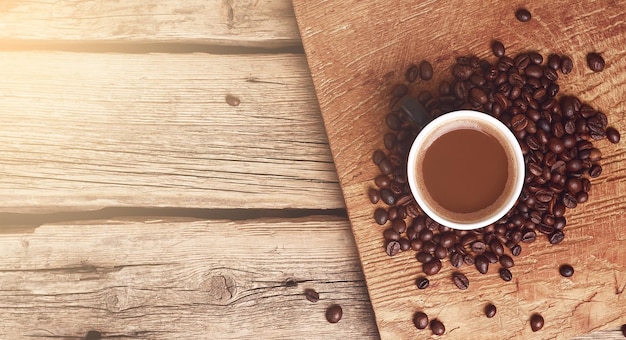 Cup of coffee and fried grains on wooden table with copy space