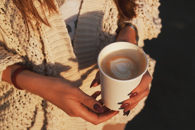 Cup of a coffee in hands. Woman's hands holding paper cup of a coffee.