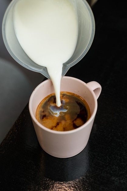 Photo a cup of coffee is being poured into a pink mug.