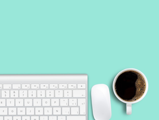 Cup of coffee and keyboard with mouse on green table background