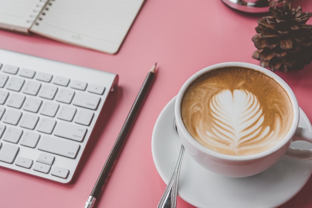 cup of Coffee latte art Heart shape with office tools on pink table