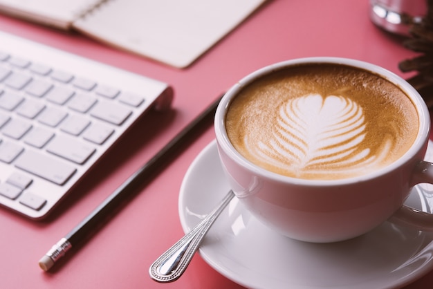 cup of Coffee latte art Heart shape with office tools on pink table