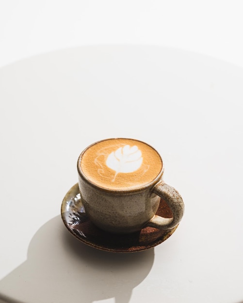 Cup of coffee latte on white table at coffee shop in morning time