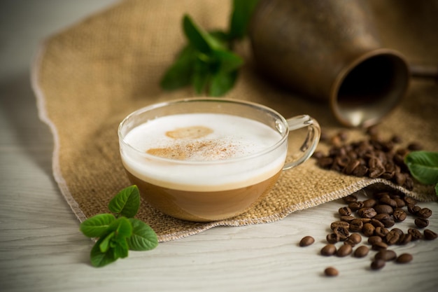 Cup of coffee latte with heart shape and coffee beans on old wooden background