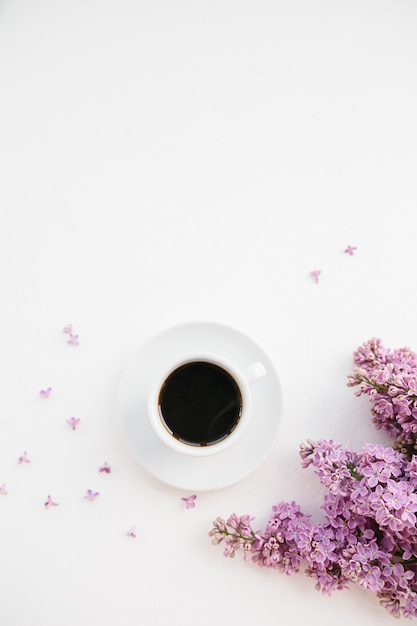 Cup of coffee and lilac branch on white 