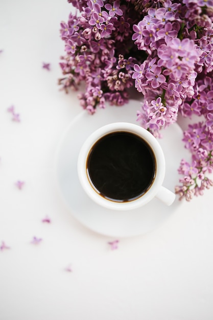 Cup of coffee and lilac branch on white 