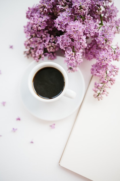 Cup of coffee and lilac branch on white