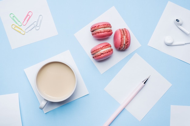 Cup of coffee, macaroon cookies and notepad  with flat lay