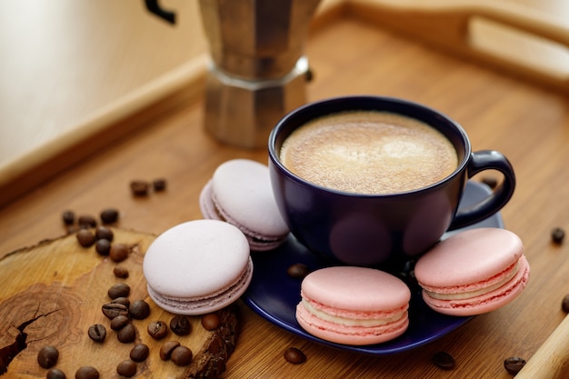 Cup of coffee macaroons and coffee beans on a platter and geyser coffee maker on a wooden tray