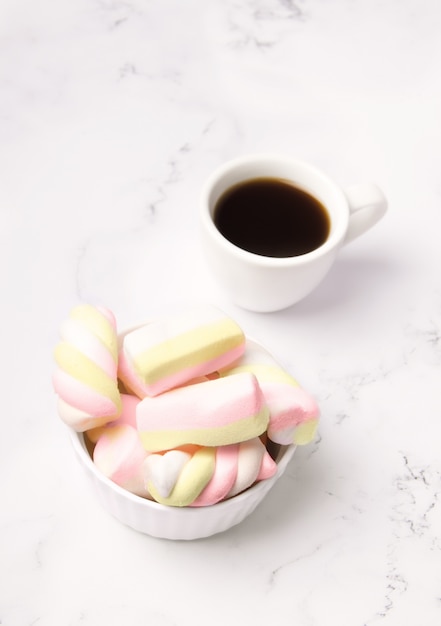 Cup of coffee next to marshmallows on a marble table