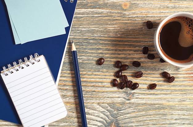 Cup of coffee and notepad on the wooden table