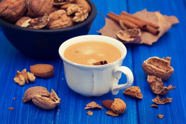 A cup of coffee and nuts on wooden surface