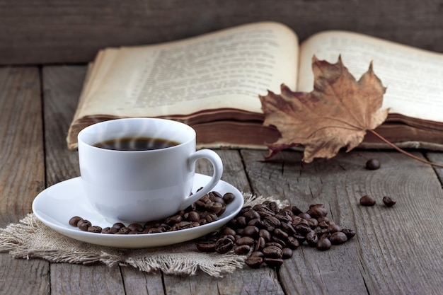 Cup of coffee and old book with autumn leaf