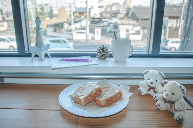 Cup of coffee and Peanut butter bread on wooden bar near glass window. traveller plan to go.