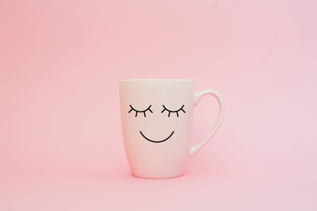 Cup of coffee on pink background with happy smile face