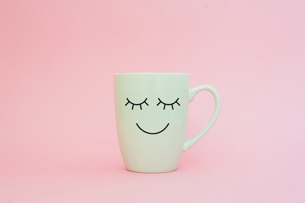 Cup of coffee on pink background with happy smile face