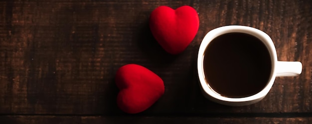 A Cup of coffee and red hearts on a dark wooden background Valentine's day Place for text place for copyingHorizontal wide photo subtitle cover copyspace