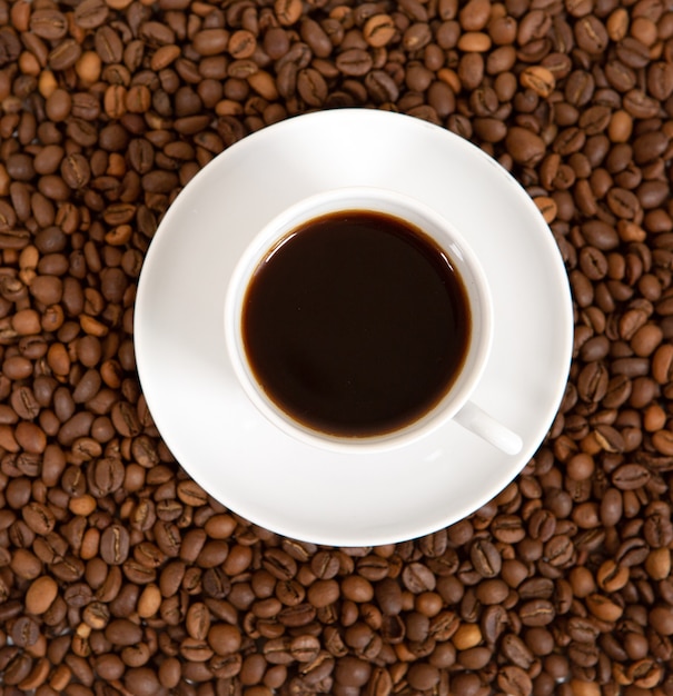 Cup of coffee on roasted coffee beans