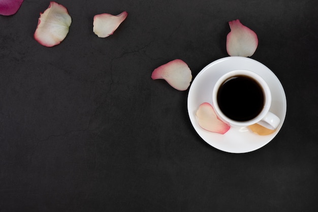 Cup of coffee and rose petals.