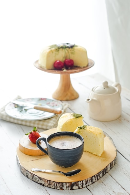 A cup of coffee served with cake on a wooden tray.