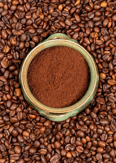 A cup of coffee sits in a pile of coffee beans.