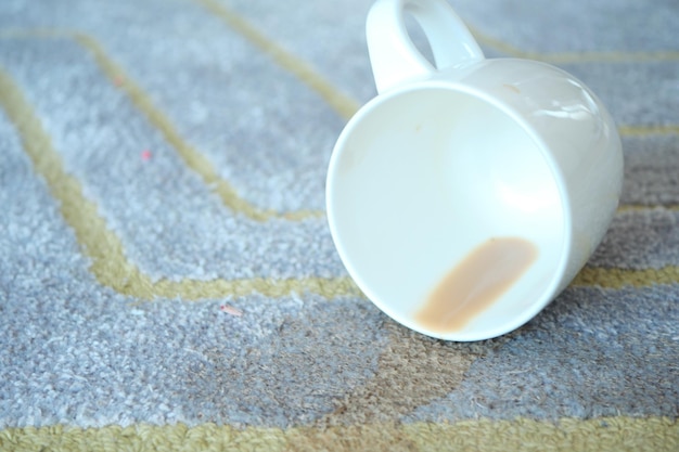 Cup of coffee spilled on gray color carpet