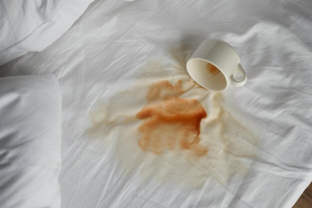 Cup of coffee spilled white bed