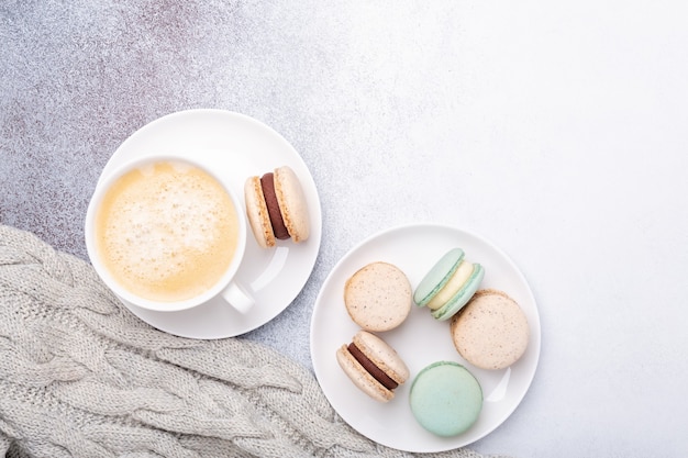 Cup of coffee, sweater and macarons on stone background. Copy space. Flat lay, top view - Image