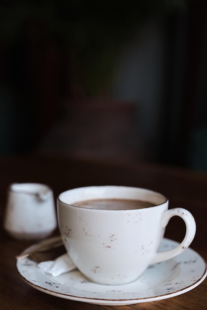 Cup of coffee on a table vintage color photograph film noise and grain in the photograph Vertical frame selective focus blurred background Idea for screensaver or menu articles about coffee