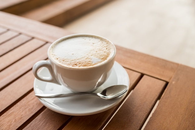 Cup of coffee on table with spoon and plate