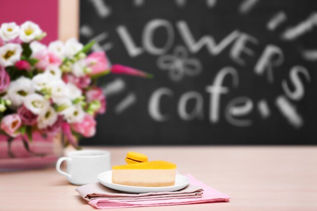 Cup of coffee tasty cake and beautiful bouquet of flowers in cafe