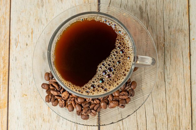 cup of coffee top view, with coffee beans over wooden table