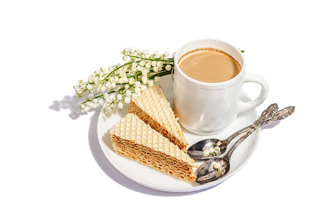 Cup of coffee and waffle cake isolated on a white background Sweet dessert with lily valley bouquet