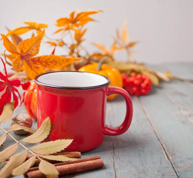 Cup of coffee with autumn leaves and small pumpkins