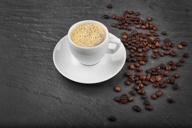 Cup of coffee with beans on grey textured background