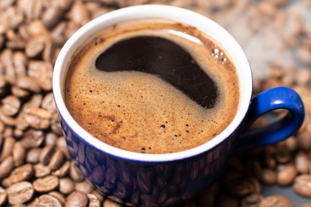 A cup of coffee with beans scattered nearby