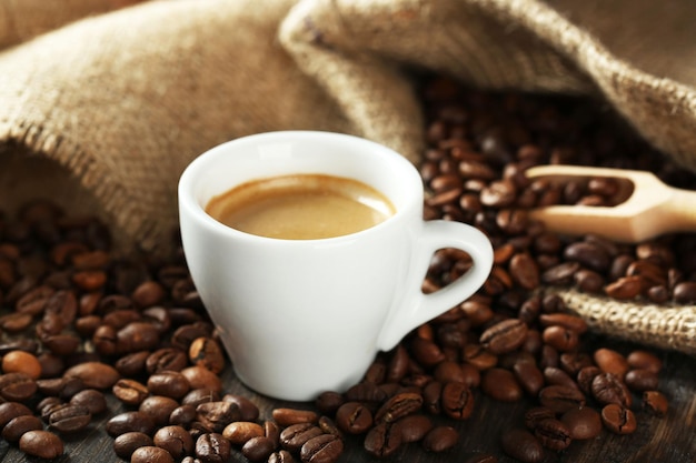 Cup of coffee with beans on table close up