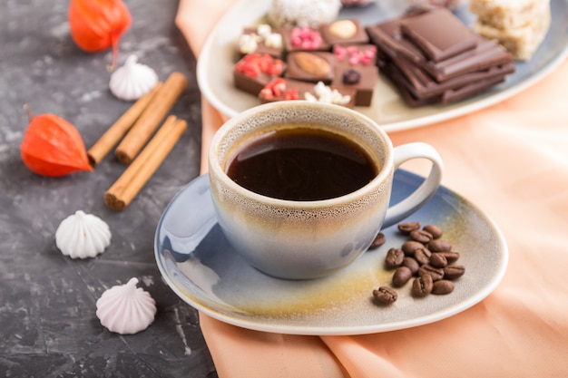 A cup of coffee with chocolate and coconut candies. side view