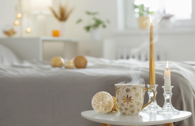 cup of coffee with christmas balls on little table in white bedroom