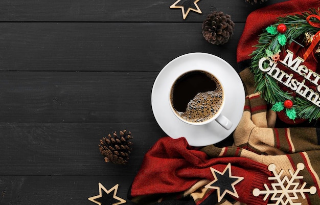 Cup of coffee with christmas decorations on black wooden table top view