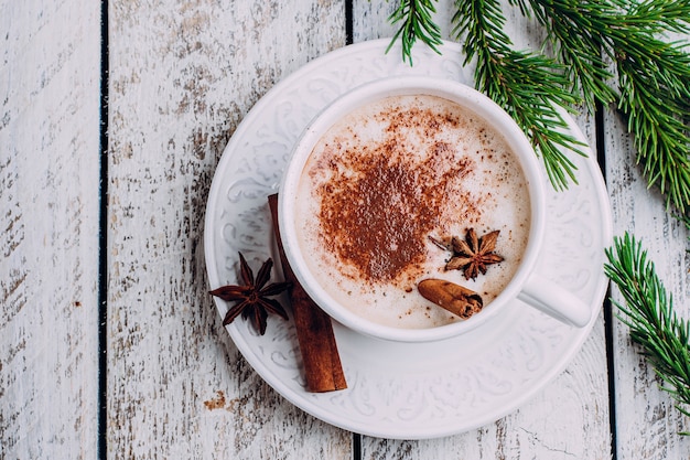 Cup of coffee with cinnamon and anice star on white wooden table. Top view, copy space. 