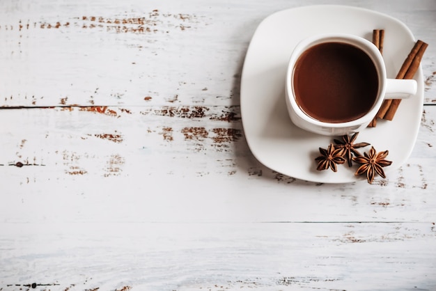 A Cup of coffee with cinnamon sticks on a light wooden