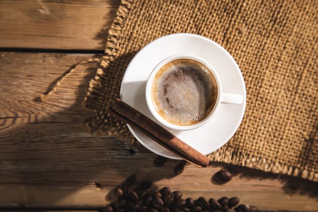 Cup of coffee with coffee beans and canvas with cinnamon