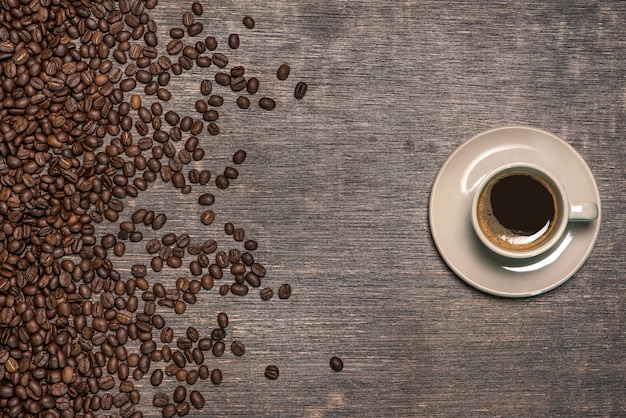 Cup of coffee with coffee beans on old table