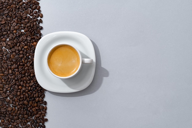 Cup of coffee with coffee beans on paper background top view