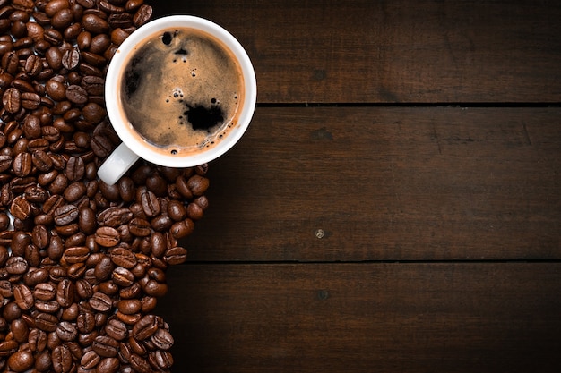 Cup of coffee with coffee beans on table